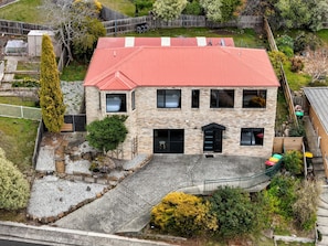 A two-story building with a red roof, multiple windows, and a paved driveway.