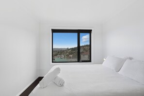 A hotel room with a bed, a large window, and a view of a residential area.