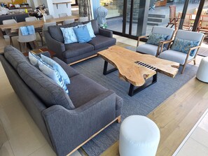 A modern living room with a sofa, armchairs, a coffee table, and a dining area.