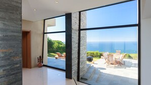 Amplia habitación con ventanas grandes que ofrecen vista al mar y al verdor.