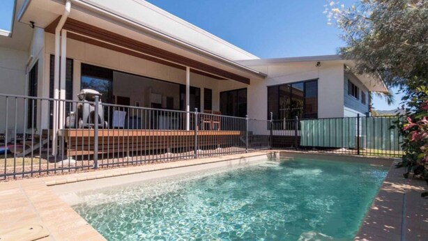 Une maison moderne dotée d’une piscine, d’un patio couvert et d’une cour arrière clôturée.