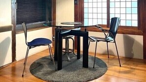 A room with a wooden floor, a round table with four chairs, a hanging light fixture, and large windows with a grid pattern. - 5 Min from Seoul Station! Authentic meets Modern & Cozy Retreat (Seoul)