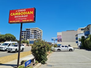 A parking lot with a sign for Samari Cambodian Restaurant, a modern building, and a billboard.