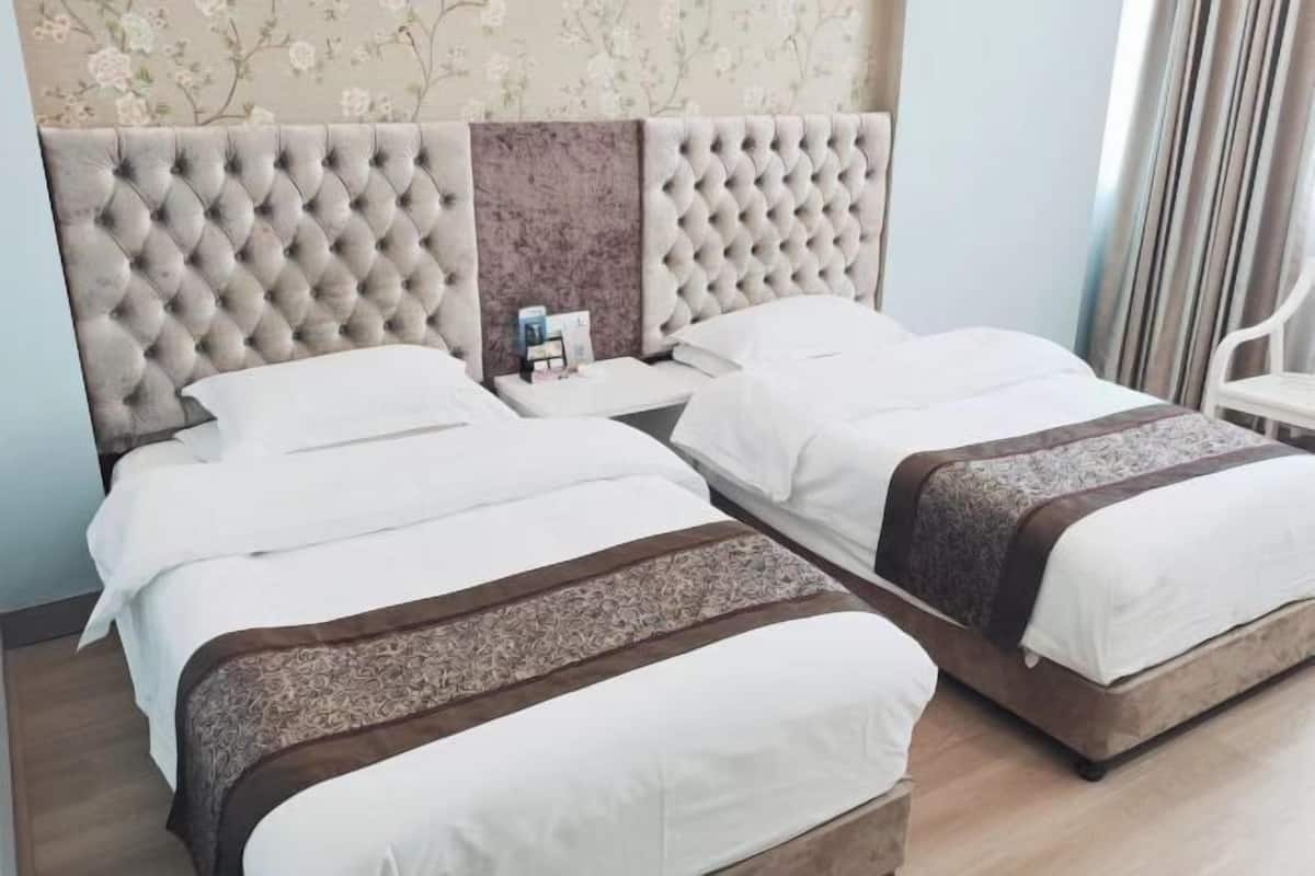 Ein Doppelbett mit einem karrenbepflegten Kopfteil, ein Nachttisch mit Lampe und ein floraler Wandbehang.