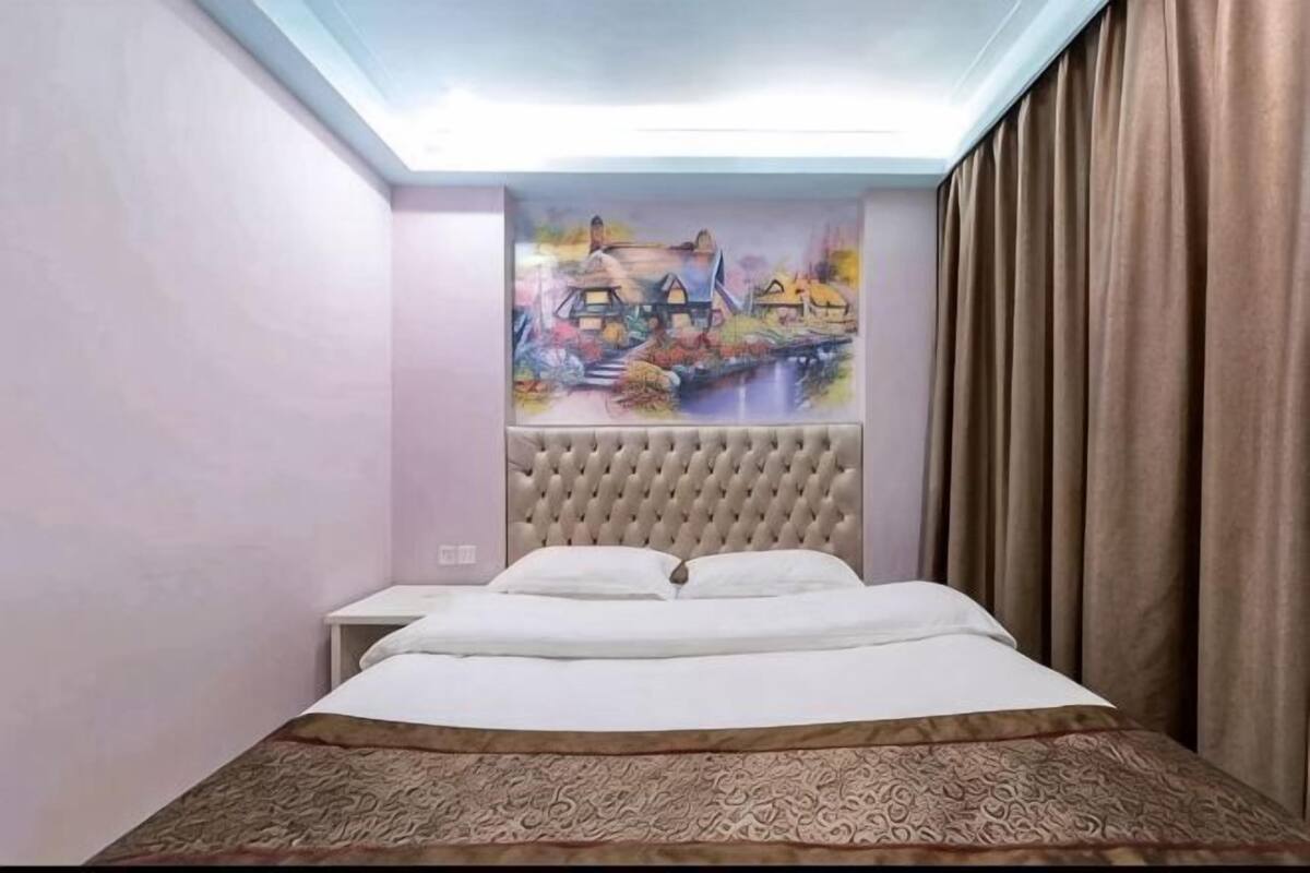 Ein Hotelzimmer mit Bett, Nachttisch und einem Gemälde an der Wand.