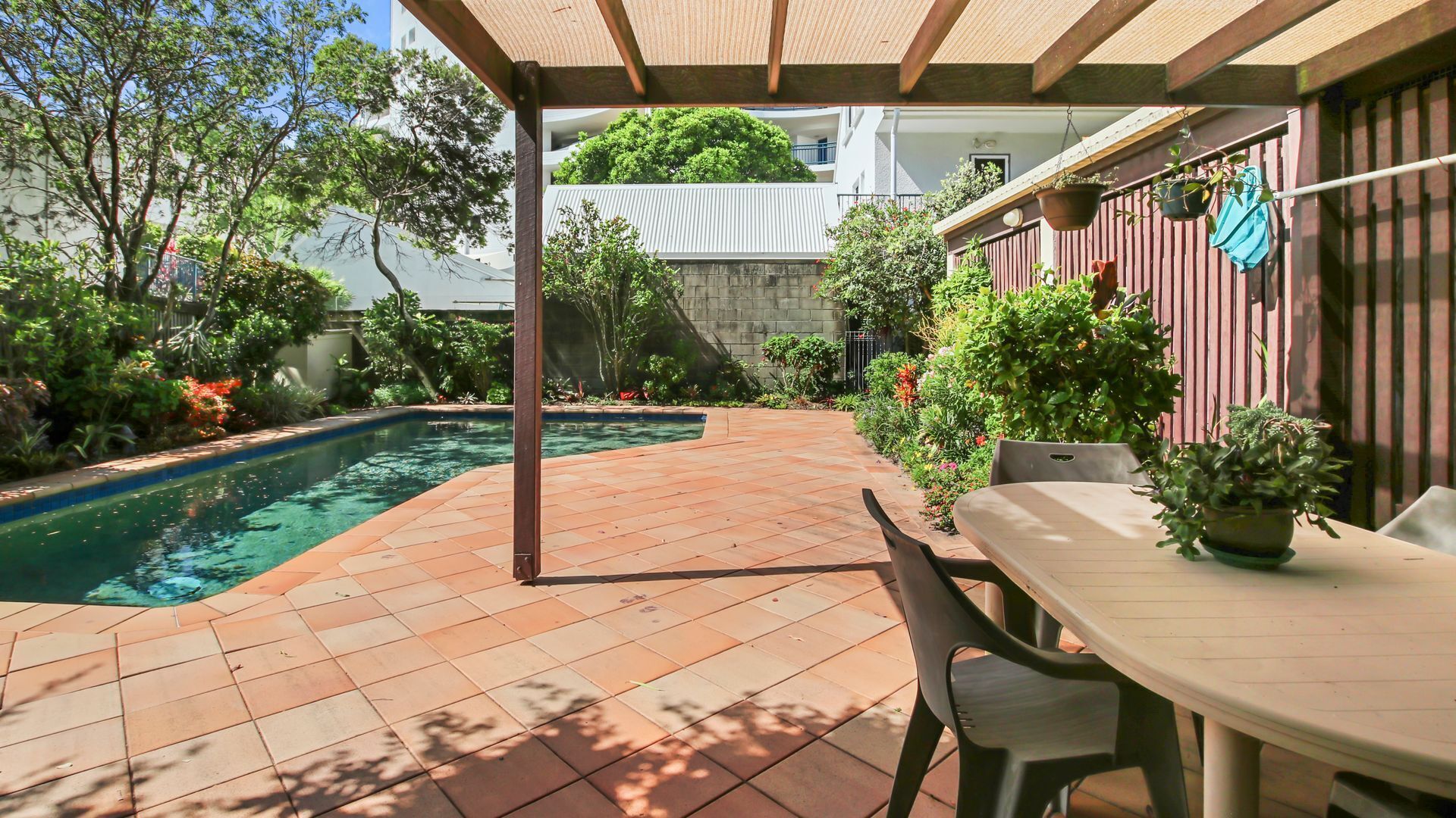 A covered patio area with a pool, outdoor seating, and potted plants.