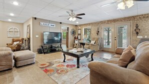 A spacious living room with a large television, comfortable seating, a coffee table, and a ceiling fan. - Your PRIVATE Hot Springs Lake Hamilton Vacation Paradise  (Royal)