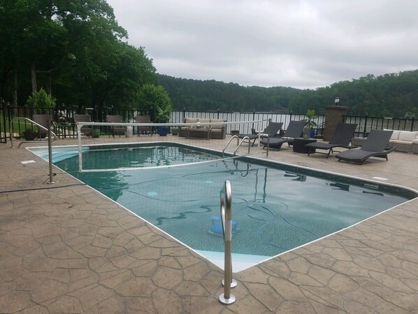 A rectangular outdoor pool with a metal ladder, surrounded by lounge chairs and a stone-tiled deck. - Your PRIVATE Hot Springs Lake Hamilton Vacation Paradise (Royal)