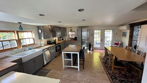 Een moderne keuken met roestvrijstalen apparatuur, een houten eettafel en een groot raam.