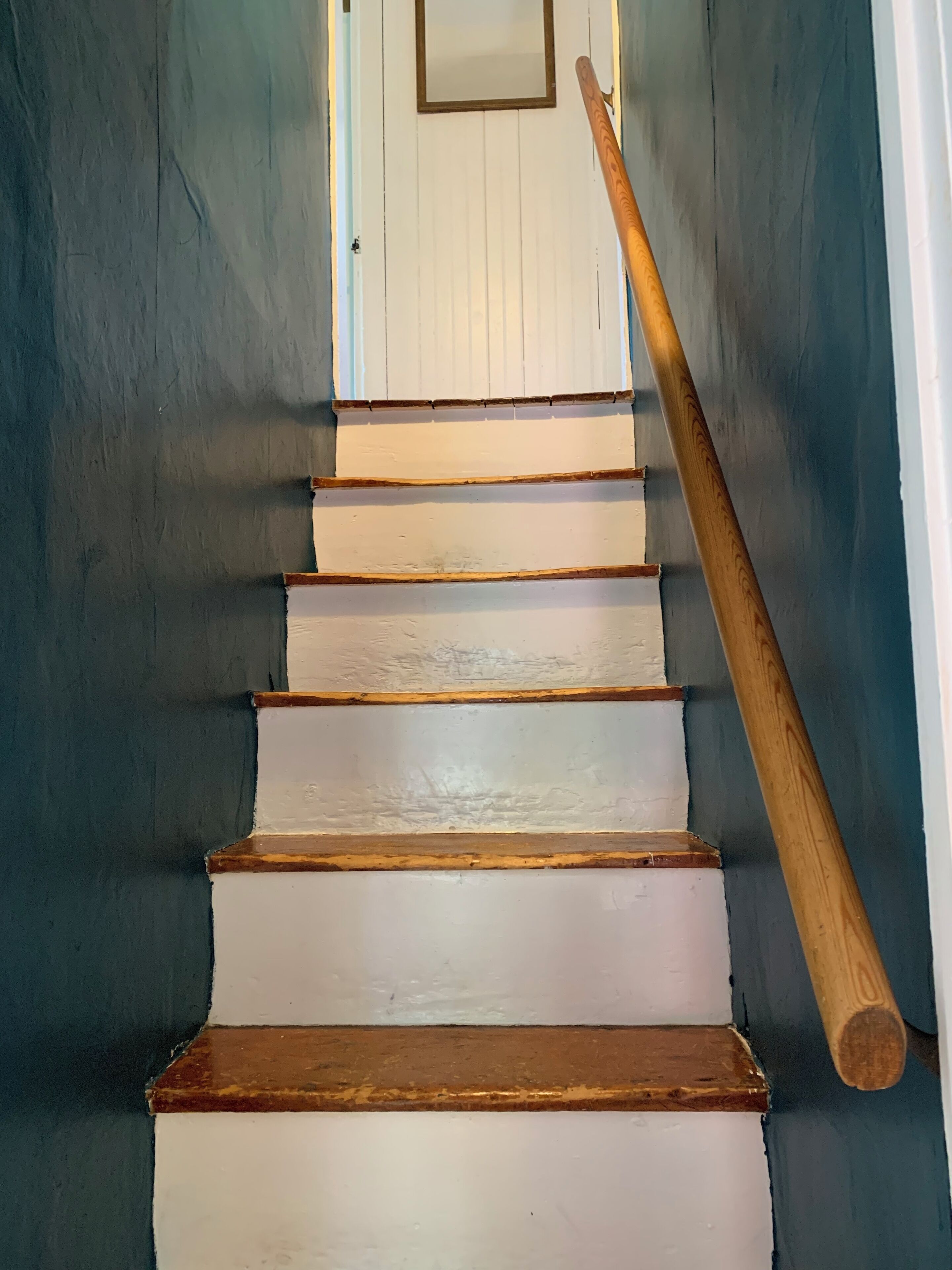 Un escalier avec des marches blanches et une rampe en bois.