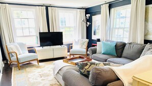 Een woonkamer met een bank, fauteuils, een televisie en een salontafel.