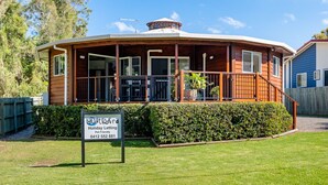 Location de vacances acceptant les animaux de compagnie, avec une façade en bois, un porche couvert et un panneau indiquant que les animaux sont les bienvenus.