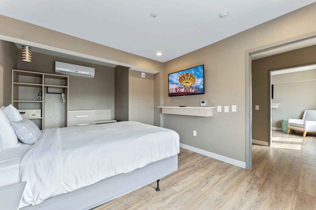 Een moderne slaapkamer met een bed, inbouwplanken, een televisie en een airconditioning.