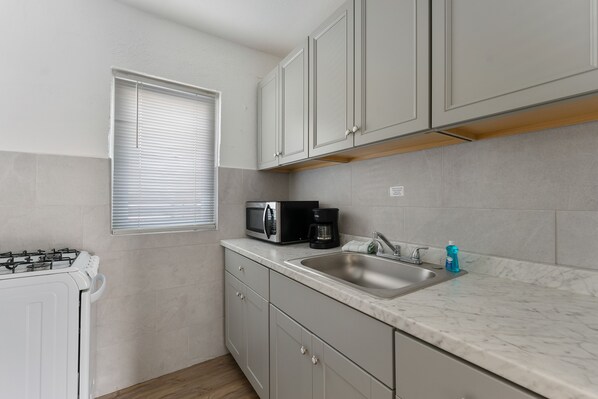 A compact kitchen with a microwave, coffee maker, and sink. - Oceanic Hotel (Wildwood)