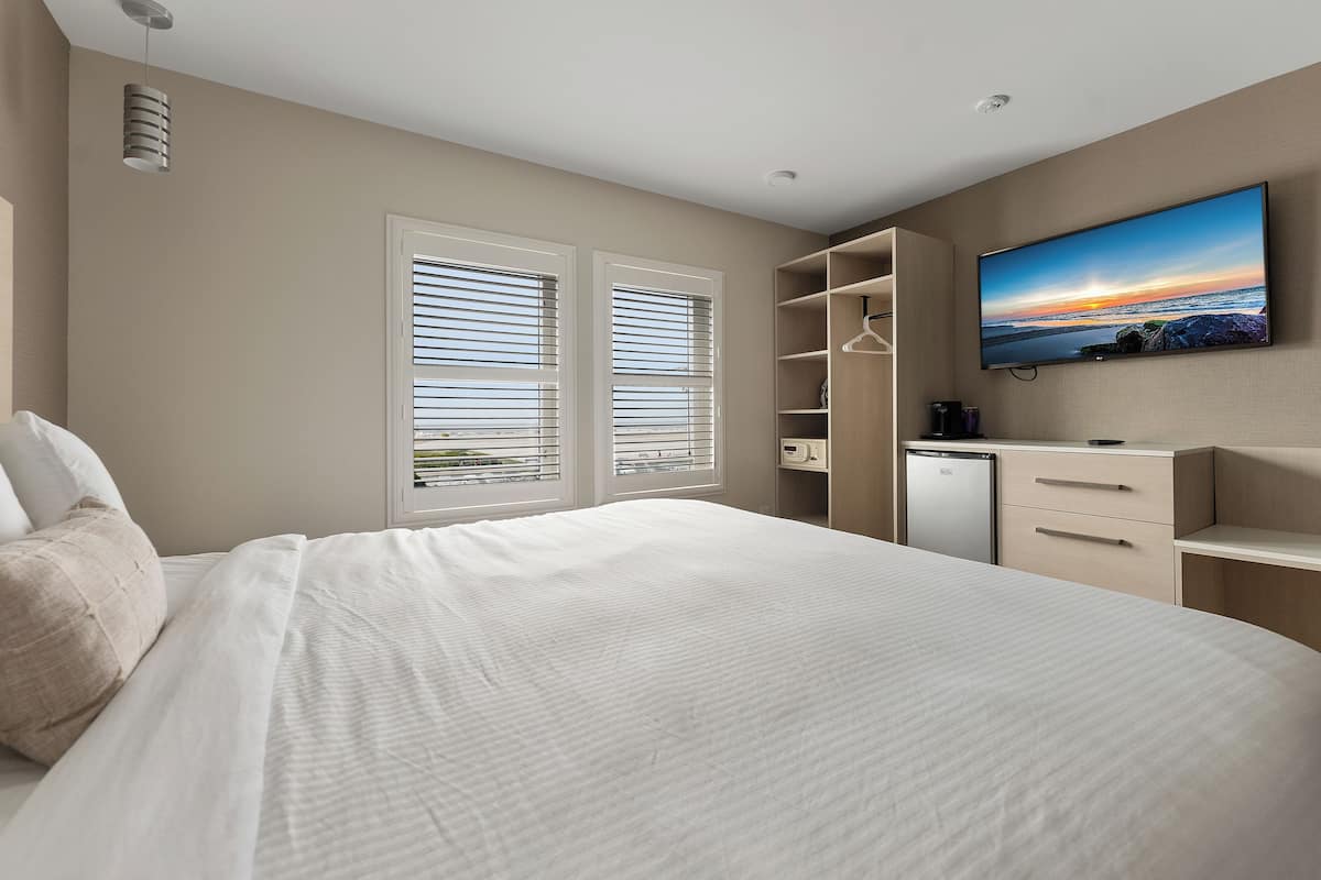 Een slaapkamer met een bed, een televisie, een kledingkast en een bureau.