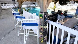 A poolside area with lounge chairs, a barbecue grill, and a pool.