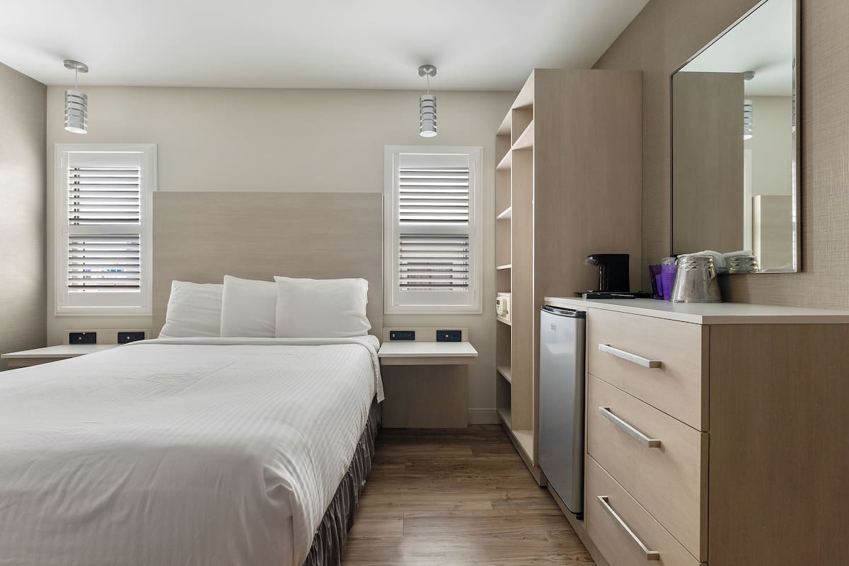 Een slaapkamer met een bed, nachtkastjes, een kaptafel, een spiegel en een ingebouwde heater.