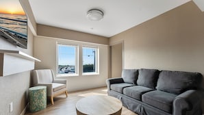 A modern living room with a grey sofa, a round wooden coffee table, and a patterned side table.