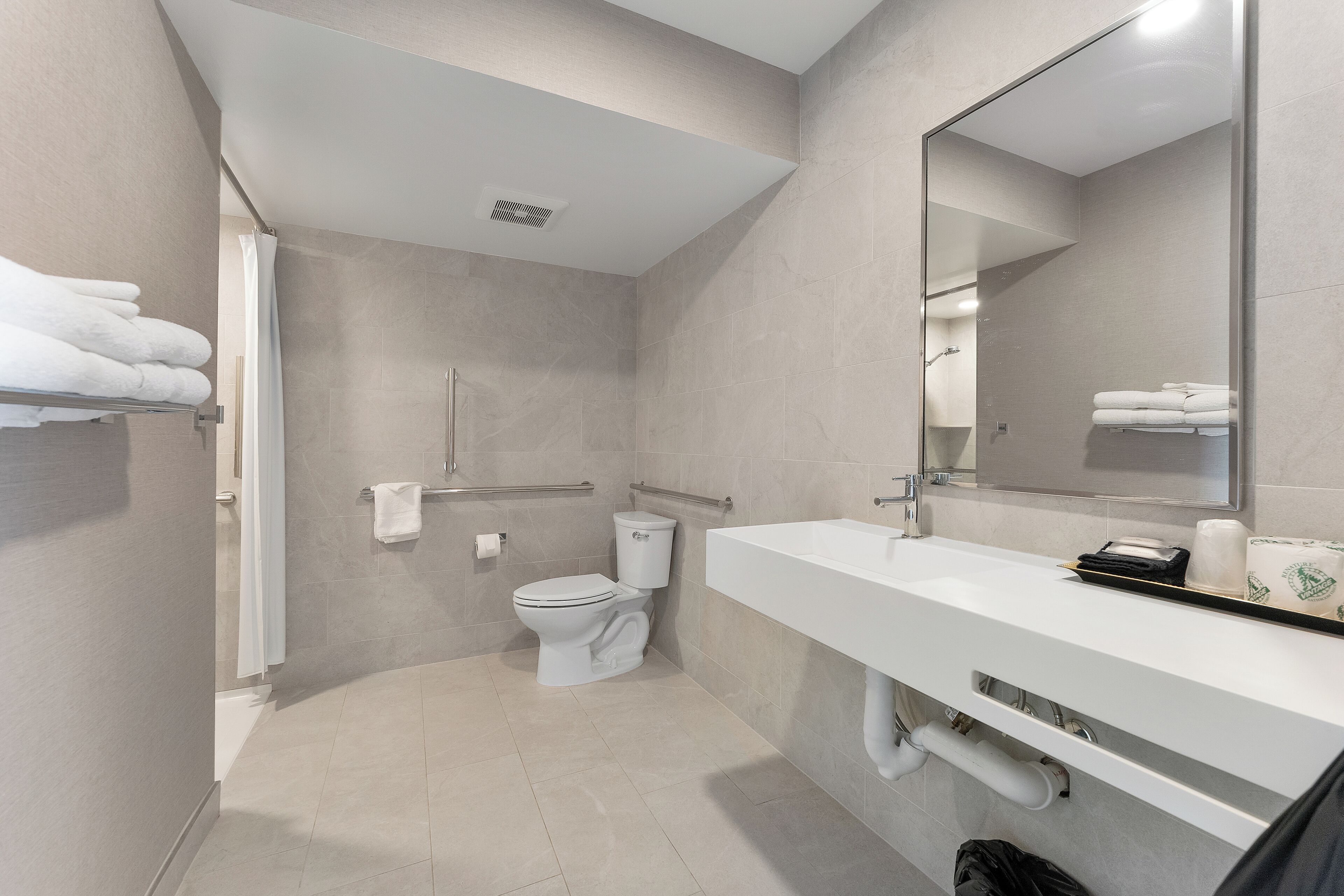A modern bathroom with a toilet, shower, and sink.