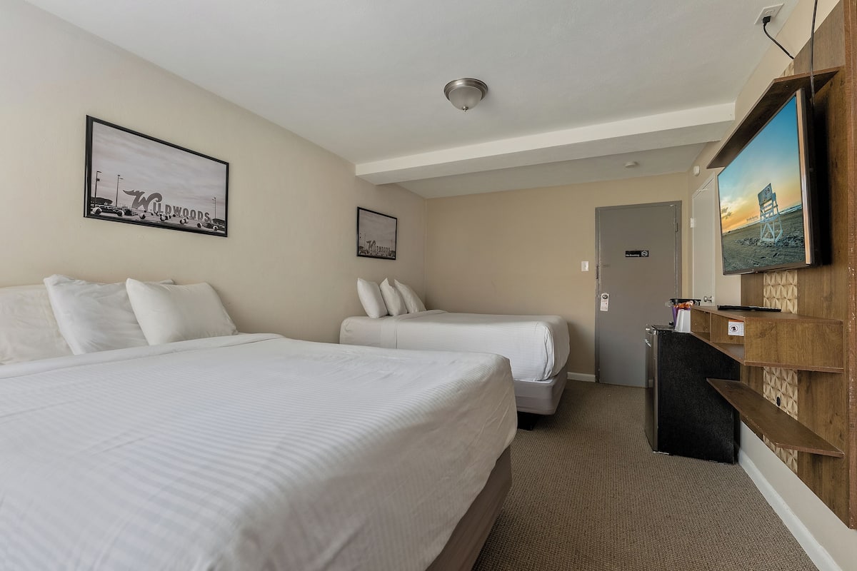 Een hotelkamer met twee bedden, een televisie, een bureau en een wandplank.