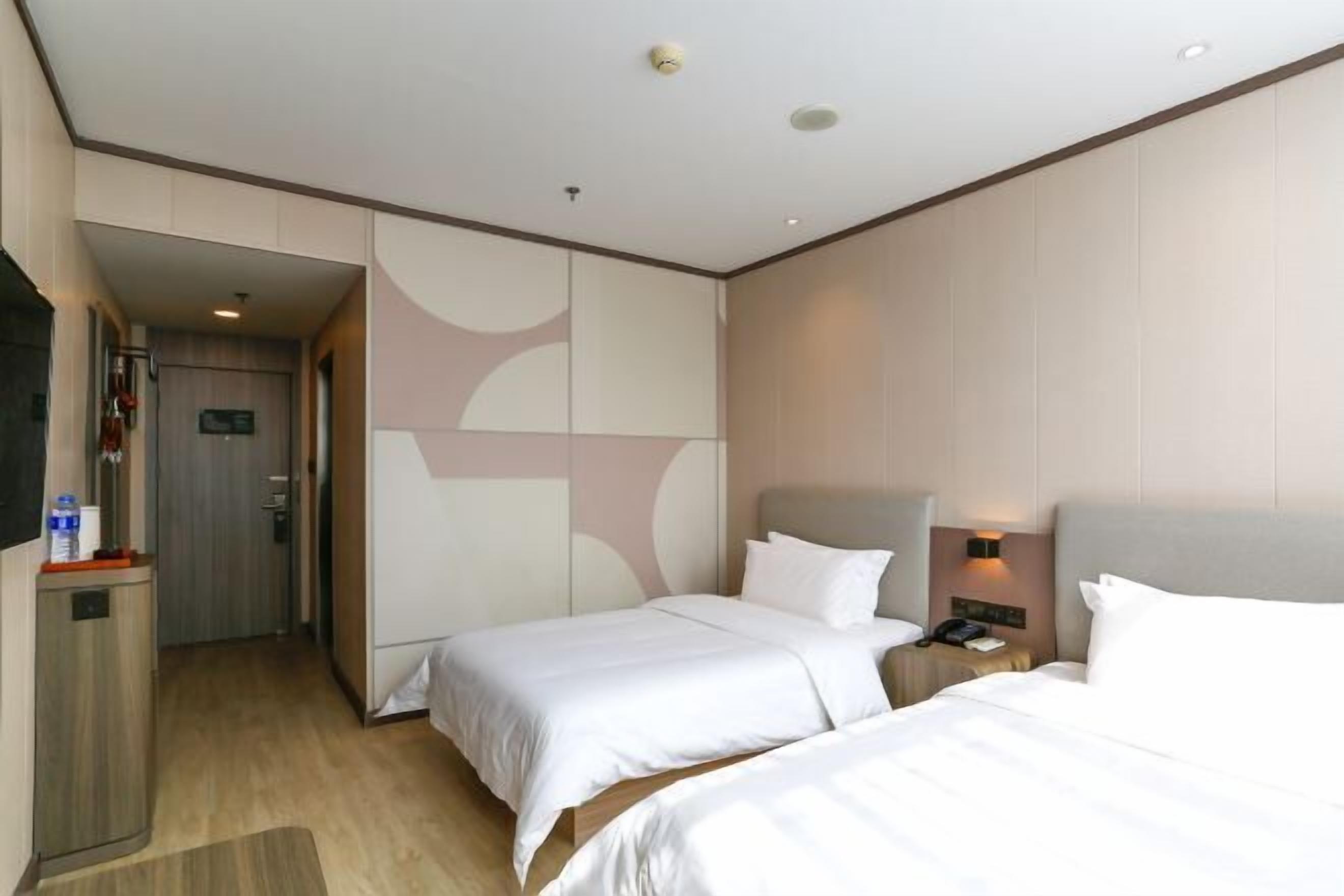 A hotel room with two beds, a desk, and a minibar.