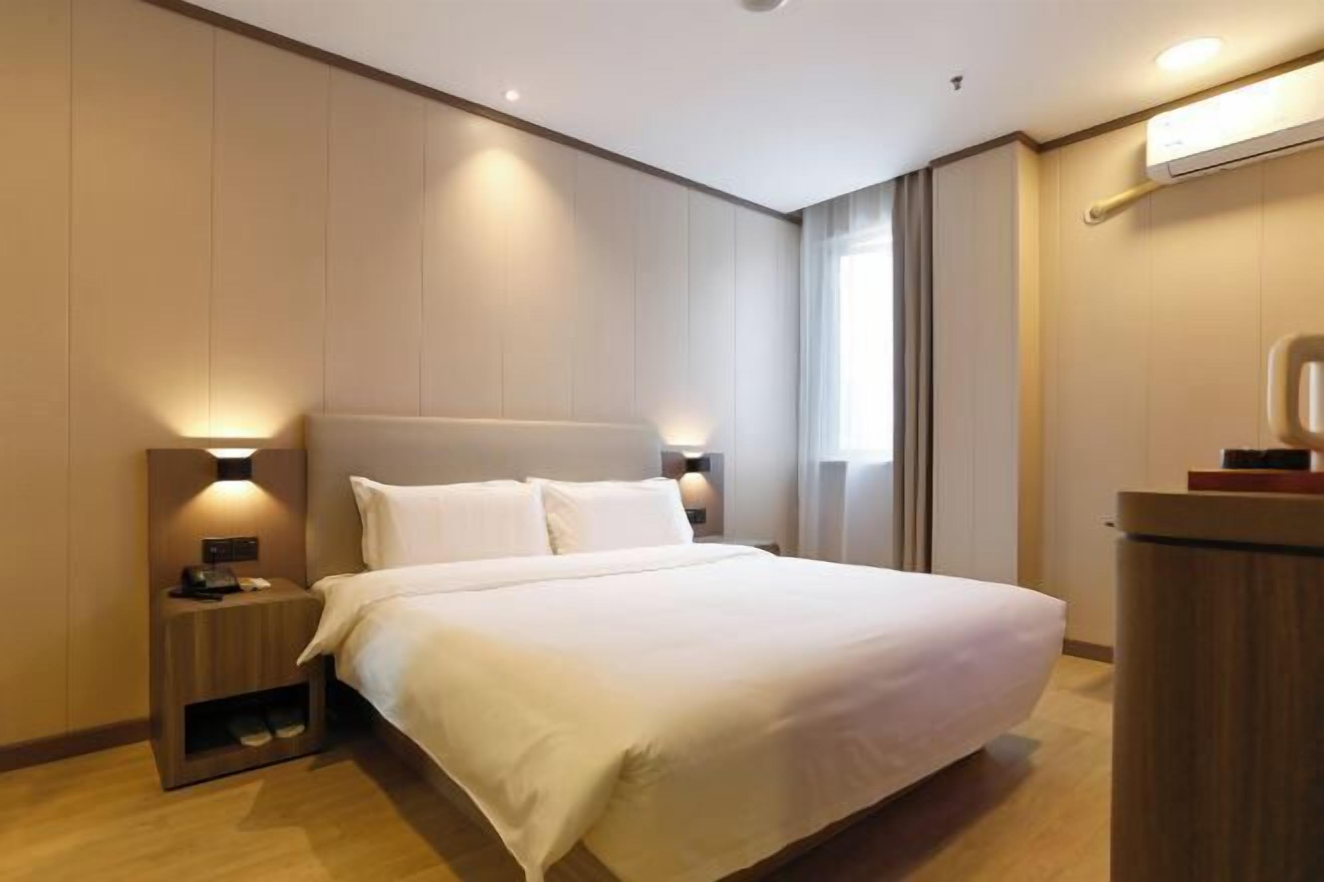 Ein modernes Hotelzimmer mit einem großen Bett, Nachttischlampen und einem Holznachttisch.