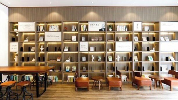 Uma biblioteca com estantes, cadeiras e uma mesa.