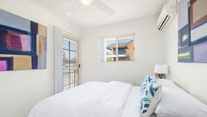 Ein Hotelzimmer mit Bett, Fenster, Klimaanlage und Bildern an den Wänden.