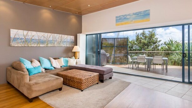A modern living room with a sofa, ottoman, and a large window to the outside. - 3 bedroom 2 bathroom spacious unit with water views. (Point Lookout)