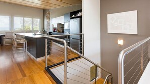 A modern kitchen with a central island, stainless steel appliances, and a view of the dining area. - 3 bedroom 2 bathroom spacious unit with water views. (Point Lookout)
