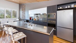 A modern kitchen with a large island, stainless steel appliances, and a bar area with striped stools. - 3 bedroom 2 bathroom spacious unit with water views. (Point Lookout)