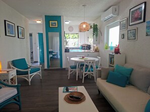 Ein Wohnzimmer mit einer Couch, Sesseln, einem Couchtisch und einem Essbereich mit Tisch und Stühlen.