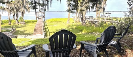 Outdoor seating chairs, a concrete pathway, and a view of a body of water.