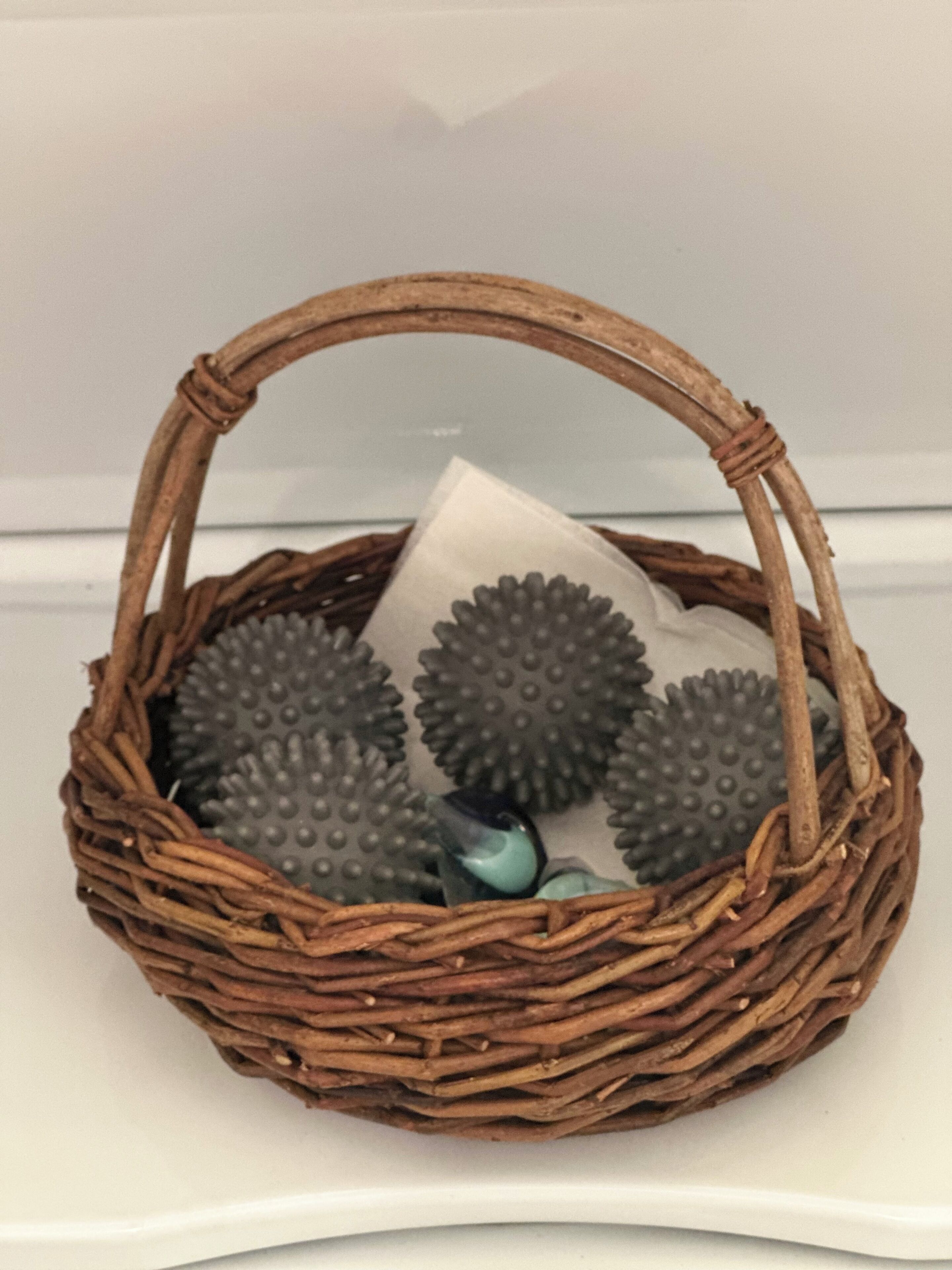 A wicker basket containing a white object and a blue object.