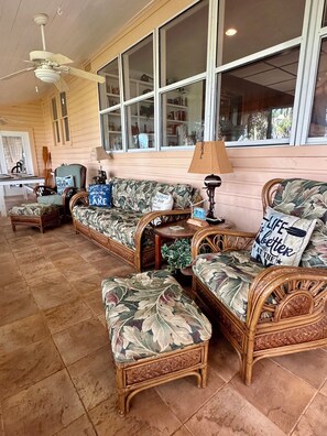 A room with wicker furniture, a ceiling fan, and large windows. - Lake living close to Gainesville, UF Health and University of Florida (Melrose)