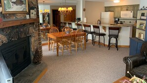 A dining area with a fireplace, a kitchen with a microwave, and a living room with a leather couch. - Ski In - Ski Out Condo in OberTal 'F' Building! (Stratton Mountain)