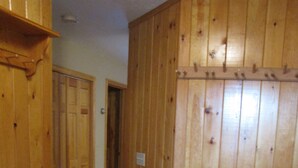 A hallway with wooden walls and tiled flooring, leading to a door. - Ski In - Ski Out Condo in OberTal 'F' Building! (Stratton Mountain)