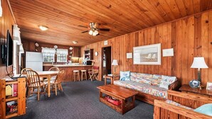 A wooden interior with a dining area, kitchen, and seating area.