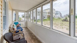 A covered porch with a view of houses and a picnic table in the background.