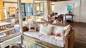 Ein gemütlicher Wohnbereich mit einem Rattan-Sofa, einem Esstisch und Stühlen.