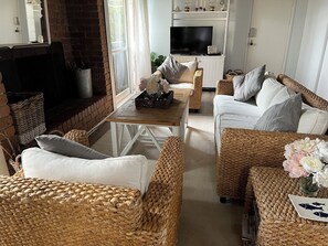 Cozy living room with a brick fireplace, comfortable sofa, and armchair, perfect for relaxing.