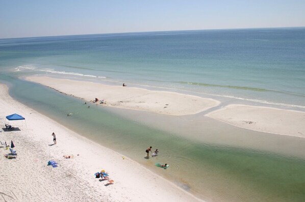 A beach with clear waters, a sandy shore, and a few people and umbrellas. - Three Bedroom Beachfront Condo at Pinnacle Port  (Panama City Beach)