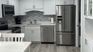 A modern kitchen with white cabinetry, a stainless steel refrigerator, a dishwasher, and a built-in oven. - Three Bedroom Beachfront Condo at Pinnacle Port  (Panama City Beach)