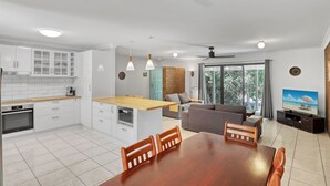 A modern kitchen with white cabinets, a wooden dining table, and a built-in oven. - Pets Allowed in this comfortable three bedroom house centrally located. (Point Lookout)