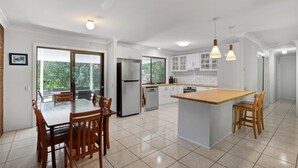 A modern kitchen with a central island, wooden dining table, and chairs. - Pets Allowed in this comfortable three bedroom house centrally located. (Point Lookout)