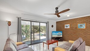 A modern living room with a sofa set, a coffee table, and a TV against a brick wall. - Pets Allowed in this comfortable three bedroom house centrally located. (Point Lookout)