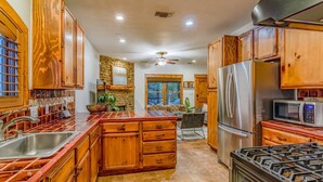 A spacious kitchen with wooden cabinets, stainless steel appliances, and a central island. - ATX Hideaway - Heated Pool / Jacuzzi / Firepit / Sleep 14 (Austin)