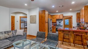 A spacious kitchen with wooden cabinets, a central island with stools, and a ceiling fan. - ATX Hideaway - Heated Pool / Jacuzzi / Firepit / Sleep 14 (Austin)