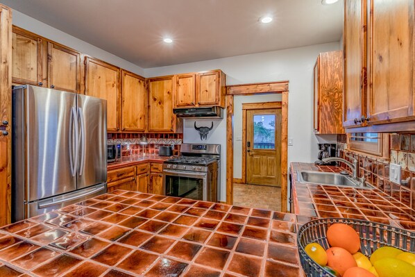 A kitchen with wooden cabinets, stainless steel appliances, and a tiled backsplash. - ATX Hill Country Hideaway (Austin)