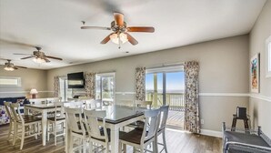 Un comedor amplio con una mesa grande y sillas, ventiladores de techo y vistas al exterior.